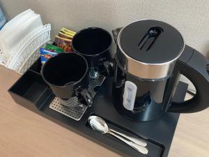 a coffee pot and three cups on a tray at AiRom Hotel in Atyrau