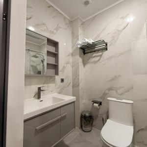 a white bathroom with a sink and a toilet at AiRom Hotel in Atyrau +13 photos
