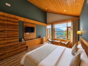 a bedroom with a large bed and a large window at Doris Mountain Cabins Tirthan Jibhi in Banjār