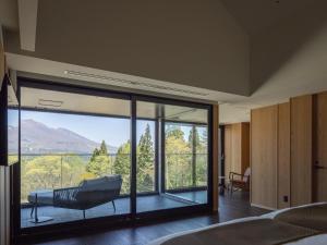 a bedroom with a large glass window with a view at Lomä Central Peaks in Shinano