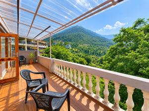 a balcony with two chairs and a view of mountains at Doris Mountain Cabins Tirthan Jibhi in Banjār