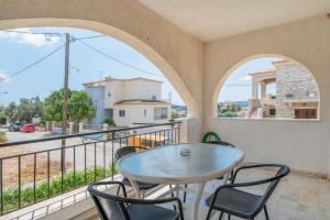 a patio with a table and chairs on a balcony at Kyma Arch House in Porto Heli