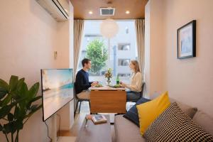 a man and woman sitting at a table in a living room at Dearcourt Kichijoji 1F-3F in Musashino