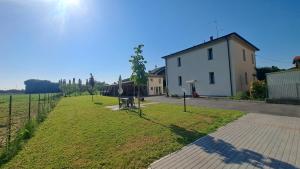 a field with a white house and a building at Tra il verde ed il Balsamico in Spilamberto