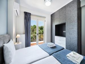 a bedroom with two beds and a tv and a window at Cataleya - Sea & Sunset View Apartment in Tsoukalades