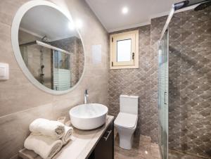 a bathroom with a sink and a mirror and a toilet at Cataleya - Sea & Sunset View Apartment in Tsoukalades