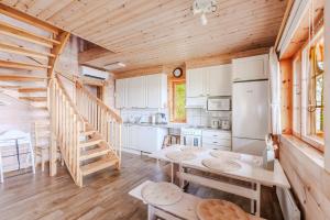 a kitchen with a table and a staircase in a cabin at Tyyni Resort - Hirsihuvila Aalto in Liperi