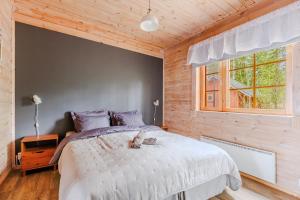 a bedroom with a large bed and a window at Tyyni Resort - Hirsihuvila Aalto in Liperi +22 photos