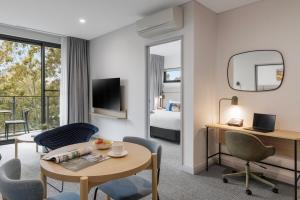 a hotel room with a bed and a table and chairs at Quest at Sydney Olympic Park in Sydney