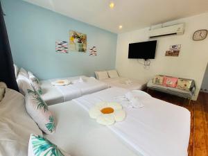 two white beds in a room with a tv at บ้านหมอบิวรีสอร์ทเชียงคาน BaanmhorbiwResortChiangKhan in Chiang Khan