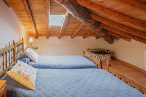 two beds in a bedroom with wooden ceilings at Casa La Romana in Ayllón