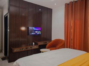 a bedroom with a bed and a tv on a wall at Maxbliss Optimum Royal Hotel in Benin City
