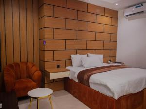a bedroom with a large bed and a chair at Maxbliss Optimum Royal Hotel in Benin City +16 photos
