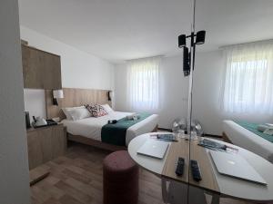 a hotel room with a bed and a table at Hotel Atena Bordeaux Sud Est - Vélo Friendly in Créon