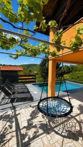 a swing hanging from a building next to a swimming pool at Holiday home Damian - Private pool in Ðurđekovec