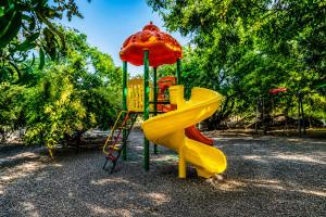 a playground with a yellow slide and an umbrella at Aatman Forest Resort - A Luxury Stay in Sasan Gir in Sasan Gir
