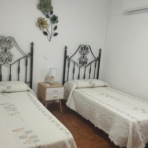 a bedroom with two beds and a table with a lamp at Casas los Rosales in Guadix
