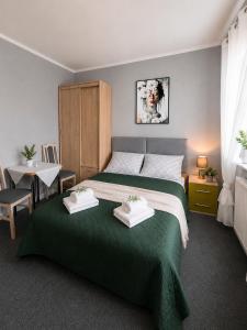 a bedroom with a green bed and a table with a chair at Pokoje gościnne Moli in Łeba