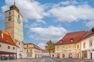 ein Uhrturm auf einem Stadtplatz mit Gebäuden in der Unterkunft Casa Weidner Hotel Sibiu in Sibiu