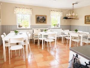 a dining room with white tables and white chairs at Valla Vandrarhem in Linköping