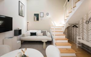 a living room with a white couch and stairs at Brixen City Maisonette in Bressanone