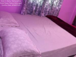 a purple bed with a purple bedspread and curtains at Hotel Pawar Palace Mahurgad in Māhūr