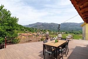 a wooden table and chairs on a deck with a view at Casa Aurora in Campo do Gerês