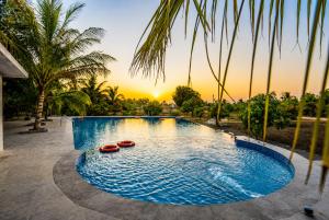 a swimming pool with two boats in the water with palm trees at Aatman Forest Resort - A Luxury Stay in Sasan Gir in Sasan Gir