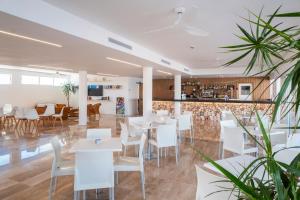 a restaurant with white tables and white chairs at Comitas Isla del Aire in Punta Prima
