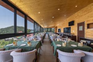 a dining room with green tables and chairs and windows at Hotel The Bliss Kufri in Kūfrī