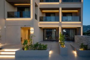 a large white building with plants in front of it at Stella Maria Hotel & Suites in Malia