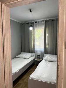 two beds in a room with a window at W sosnowym lesie 2 in Lubniewice