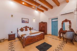 a bedroom with a bed and a desk and a mirror at La casa Verde 4BHK with Private Pool, Baga in Baga +73 photos
