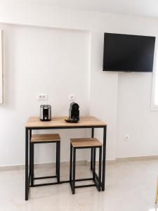 Ein Holztisch mit zwei Hockern und ein Fernseher an der Wand in der Unterkunft Theta Project in Stavros