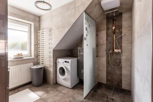 a bathroom with a washer and dryer next to a shower at DACHJUWEL Luxus - Apartment Penthouse Ferienwohnung in Leibnitz +13 photos