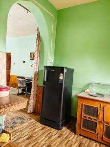 a kitchen with a black refrigerator in a room at Adarsh homestay - 1BHK in Manāli