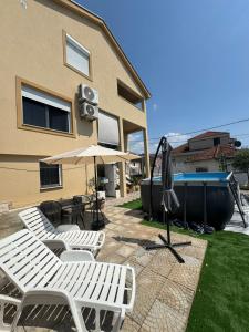 a patio with chairs and an umbrella and a pool at House 23 B2 in Tivat