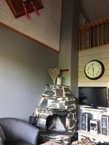 a living room with a stone fireplace and a clock at Rivitahko 5 in Tahkovuori