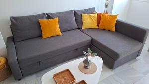 a grey couch with yellow pillows and a table at Apartamento Los Naranjos in La Línea de la Concepción