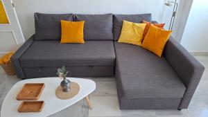 a grey couch with yellow pillows and a table at Apartamento Los Naranjos in La Línea de la Concepción +37 photos