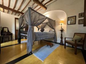 a bedroom with a canopy bed and a chair at Gratitude Heritage in Pondicherry