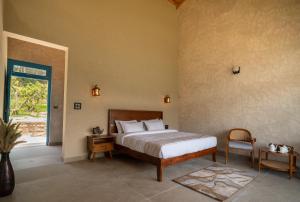 a bedroom with a bed and a chair and a window at Enchanted Hills Farmstay in Mukteshwar