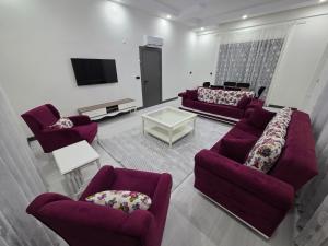 a living room with purple couches and a tv at ViLLA ANGEL AHMET HASAN in Belek