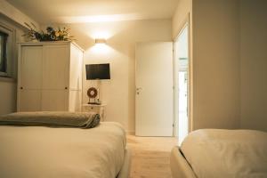 ein Schlafzimmer mit zwei Betten und einer Tür mit einem Fernseher in der Unterkunft Cà Virò - B&B sul Sentiero Valtellina in Albosaggia