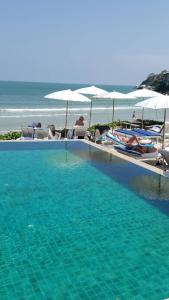a swimming pool with chairs and umbrellas on the beach at Nern Chalet Beachfront Hotel in Hua Hin