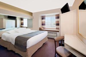 ein Hotelzimmer mit einem großen Bett und einem Schreibtisch in der Unterkunft Microtel Inn & Suites by Wyndham Joplin in Joplin