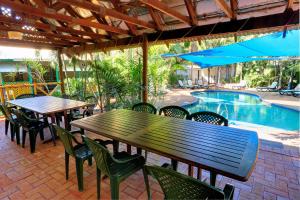 a patio with tables and chairs next to a pool at Habitat Resort in Broome