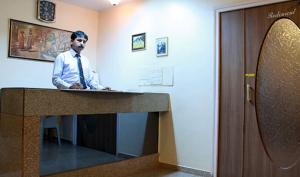 a man is standing at a desk in a room at Hotel Anando , Saputara in Saputara
