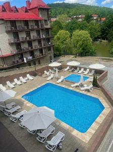 a swimming pool with chairs and umbrellas next to a hotel at Вiлла Тераса in Polyana