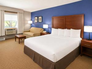 a hotel room with a large bed and a chair at Comfort Inn Iron Mountain North in Iron Mountain